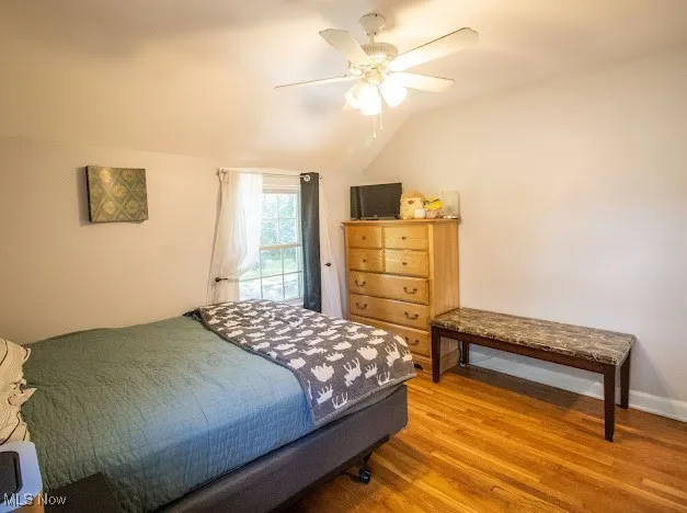 Bedroom with vaulted ceiling, wood finished floors, and a ceiling fan