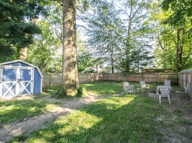 Fenced backyard featuring a storage unit