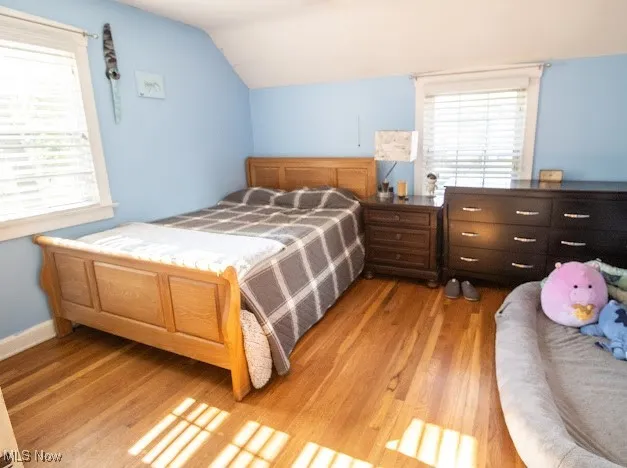Bedroom with light wood-style flooring and lofted ceiling
