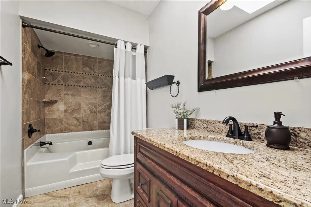 Full bath with vanity, shower / bath combo, and a skylight