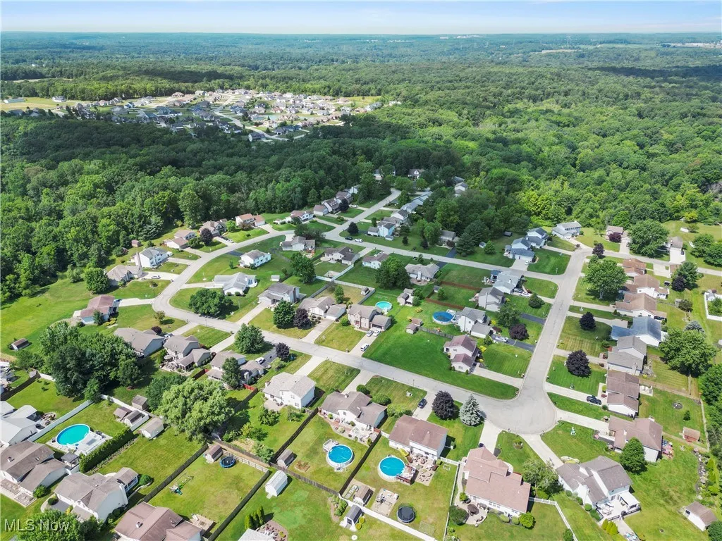 Aerial view of property and surrounding area with a forest and a pool