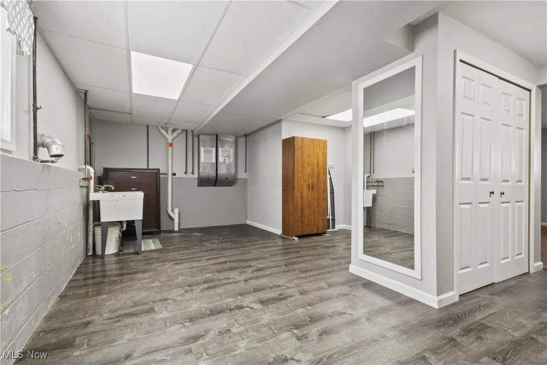Finished below grade area with concrete block wall, wood finished floors, and a paneled ceiling