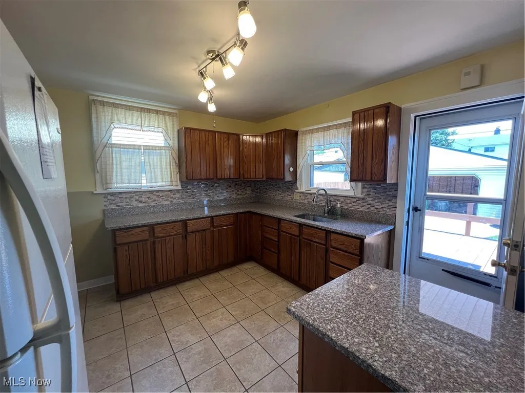 Kitchen with light tile patterned flooring, tasteful backsplash, and dark stone countertops