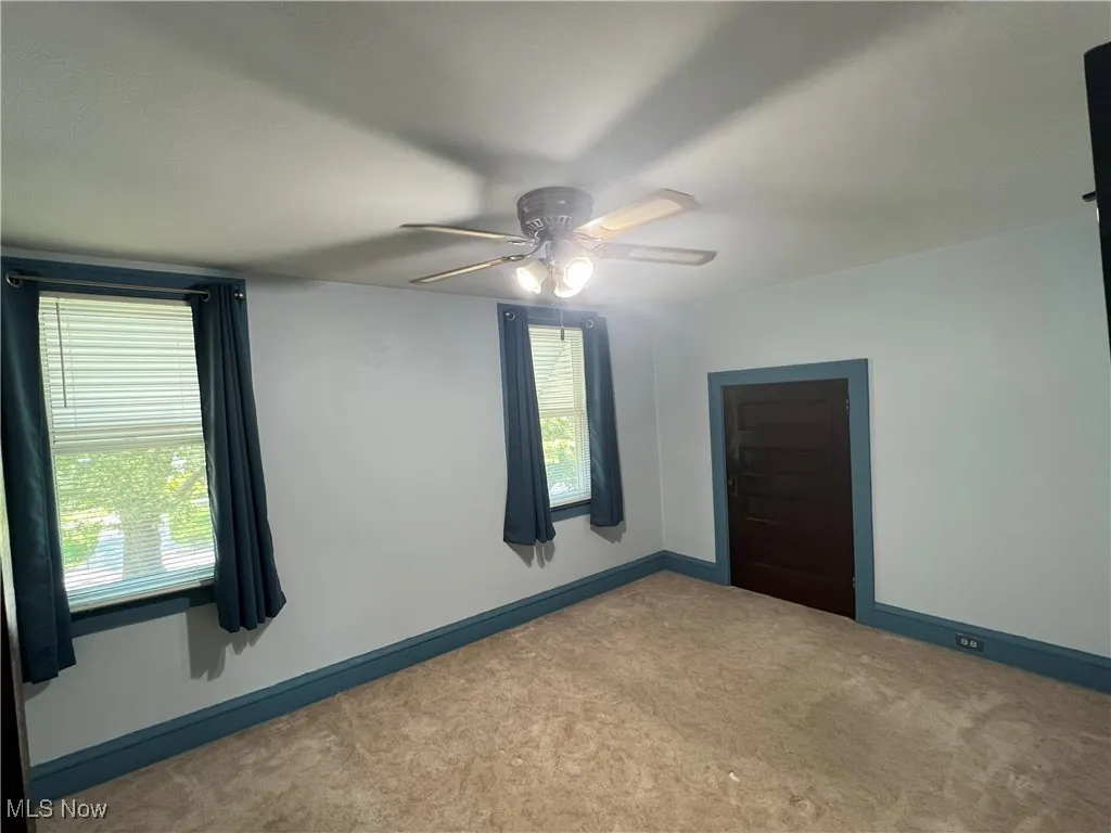 Carpeted spare room with a ceiling fan and baseboards