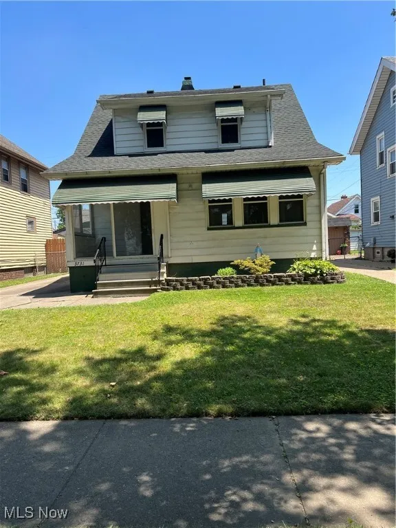 Bungalow-style home with a front lawn and roof with shingles