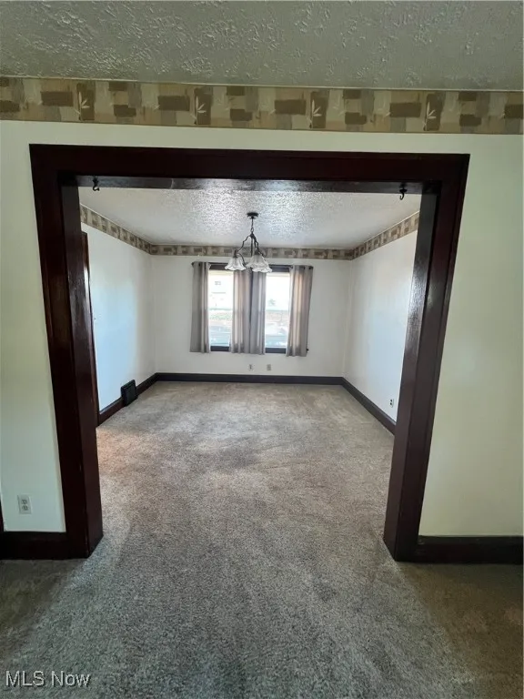 DR featuring a textured ceiling, carpet flooring, and a chandelier