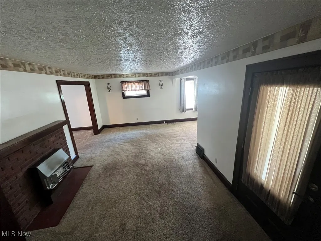  living room featuring a textured ceiling, carpet, and gas fp