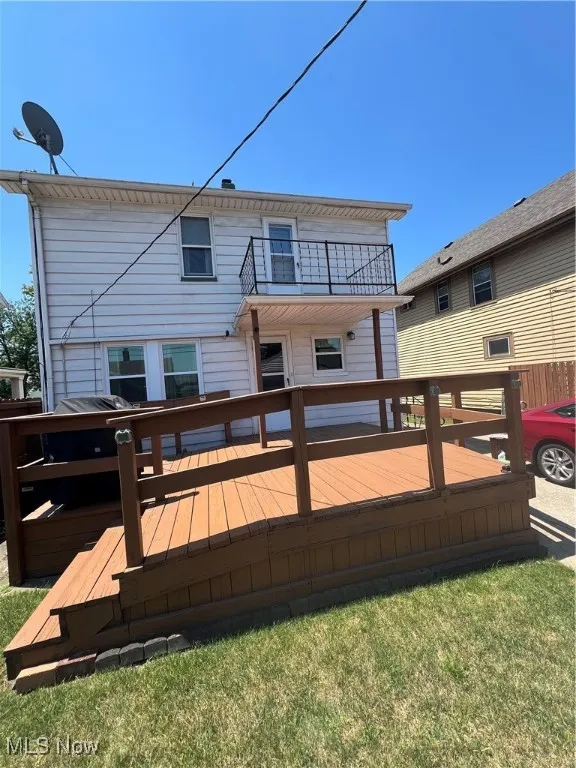 Rear view of property featuring a balcony and a wooden deck