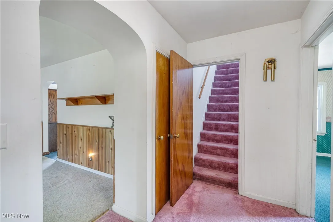 Stairs featuring carpet floors and arched walkways