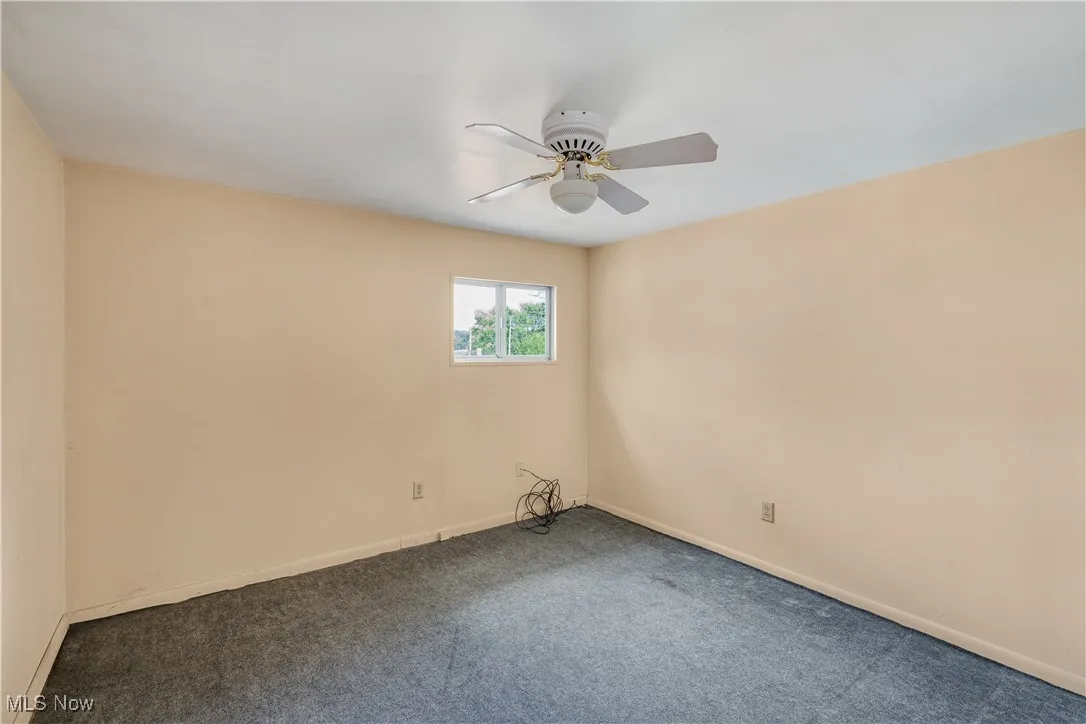 Carpeted spare room featuring a ceiling fan and baseboards