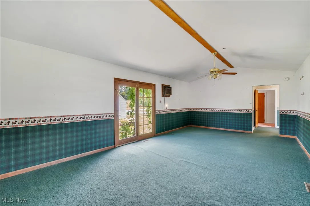 Unfurnished room with a wainscoted wall, carpet, a ceiling fan, and an AC wall unit