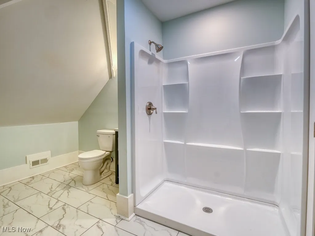 Bathroom featuring a shower stall and marble finish floors