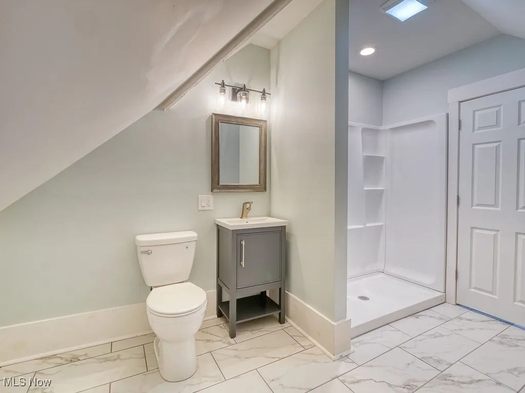 Bathroom with marble look tile flooring, vanity, a shower stall, and recessed lighting