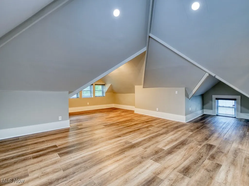 Bonus room with vaulted ceiling, plenty of natural light, and wood finished floors