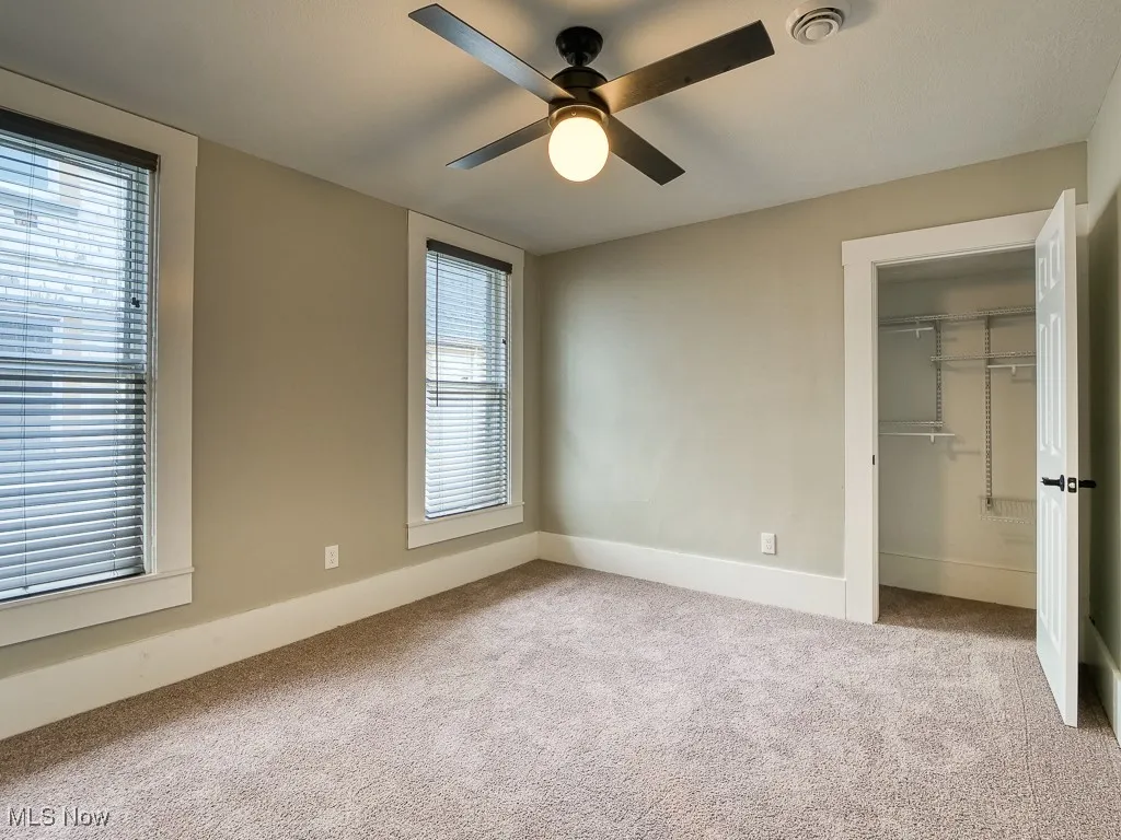 Unfurnished bedroom with carpet flooring, a closet, a spacious closet, and ceiling fan