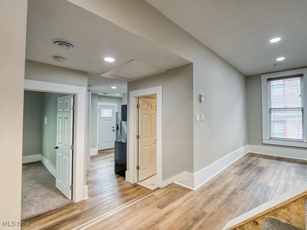 Empty room featuring light wood-style floors, a smoke detector, recessed lighting, and attic access