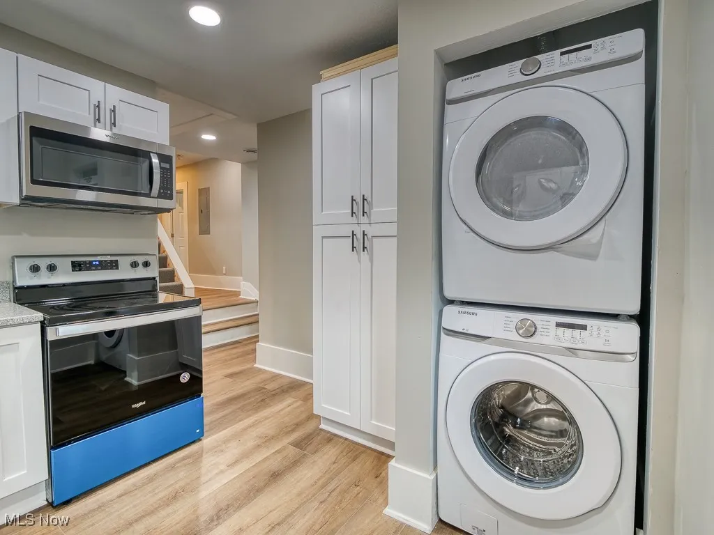 Laundry room featuring stacked washing machine and dryer, light wood-type flooring, and recessed lighting