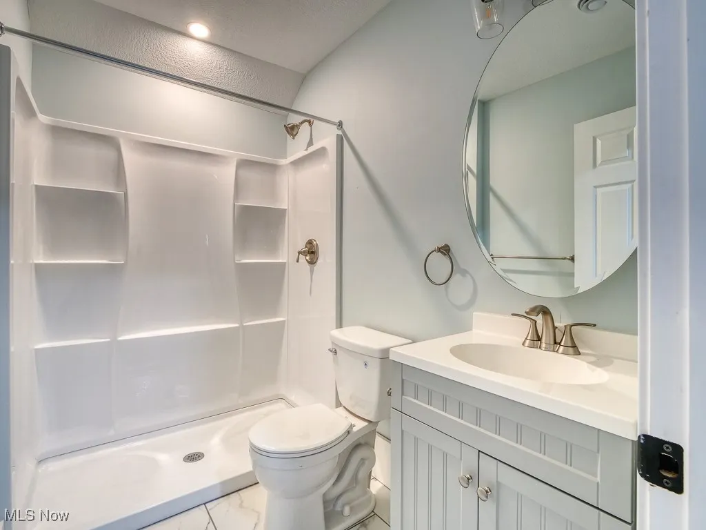 Full bathroom with marble finish floors, a shower, and vanity