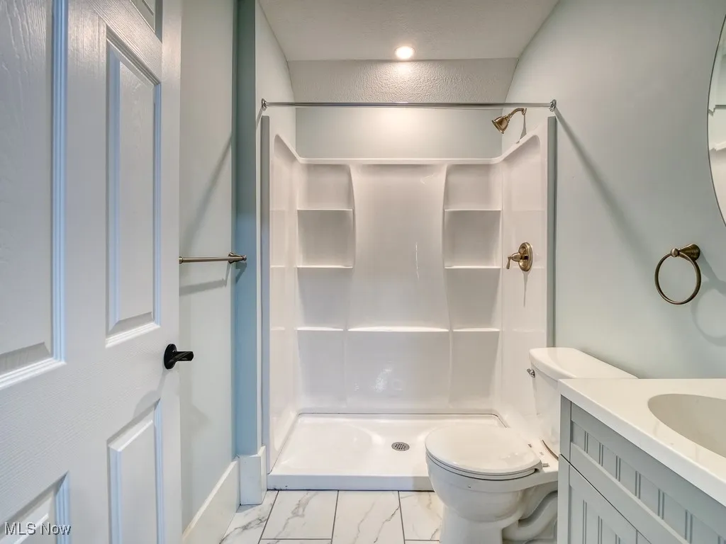 Full bathroom with marble finish flooring, a shower, and vanity