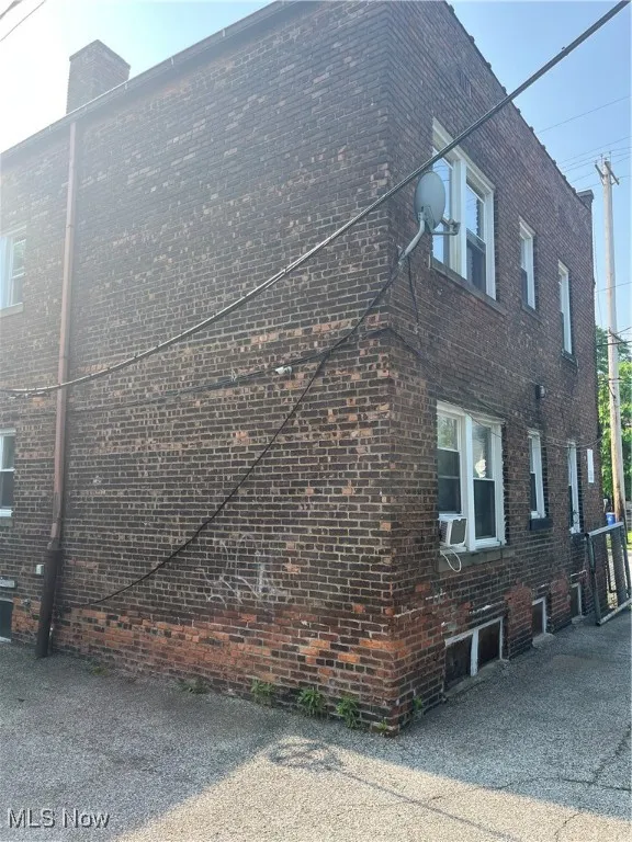 View of side of property featuring brick siding and cooling unit