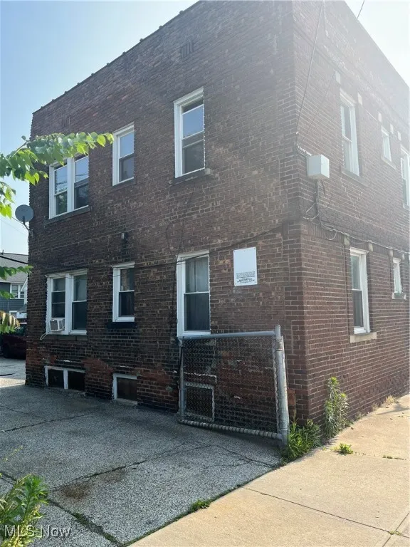 View of side of home featuring brick siding and a gate