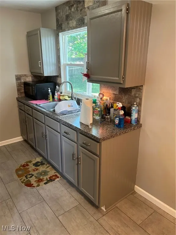 Kitchen featuring gray cabinets and decorative backsplash