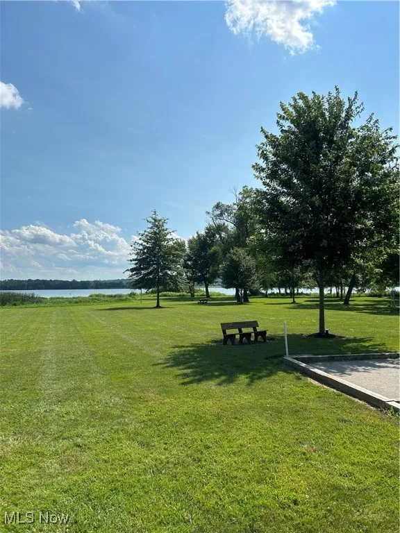 Surrounding community with a water view and a lawn