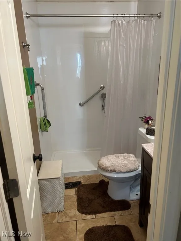 Full bath with a shower with curtain, vanity, and tile patterned floors