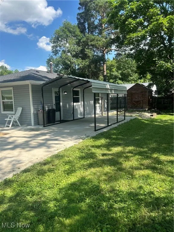 Rear view of house with a shed, driveway, and a detached carport