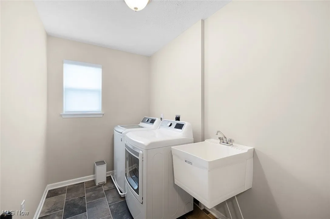 Laundry area with washing machine and dryer and dark stone finish floors