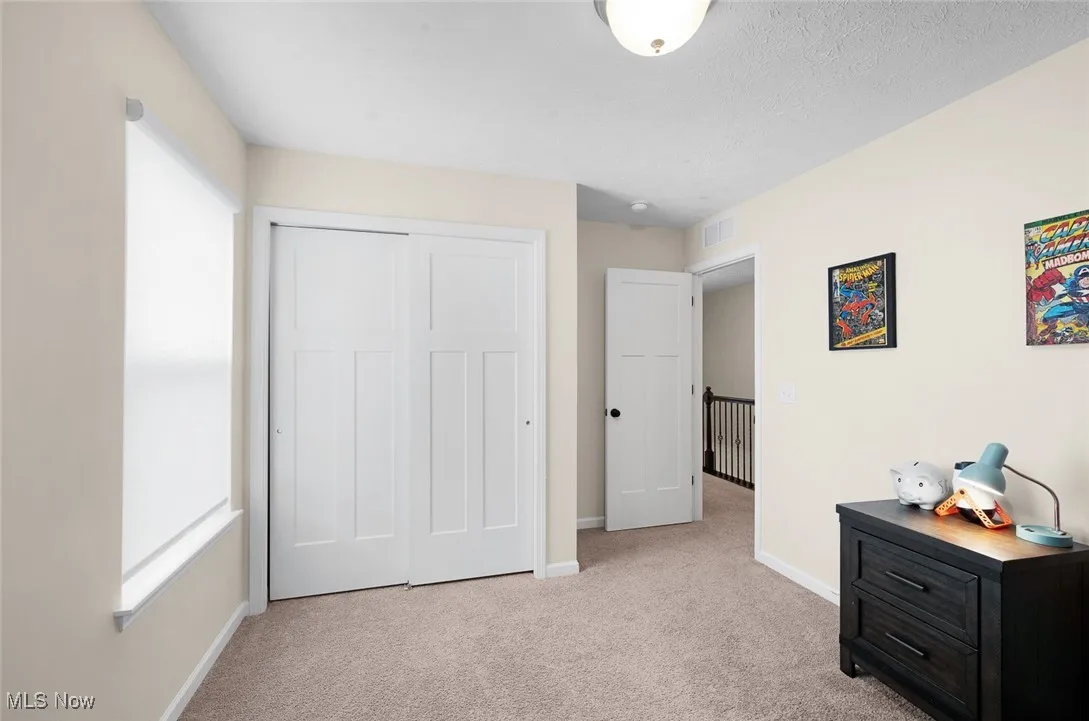 Bedroom with light colored carpet and a closet