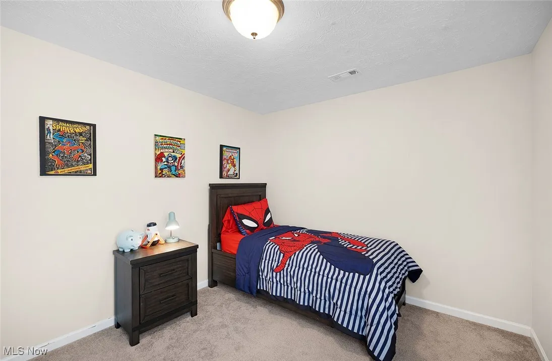 Bedroom featuring light colored carpet and a textured ceiling