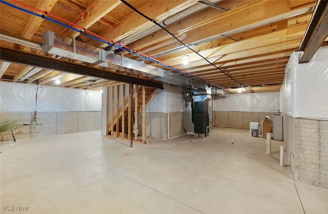 Unfinished basement featuring stairway and heating unit