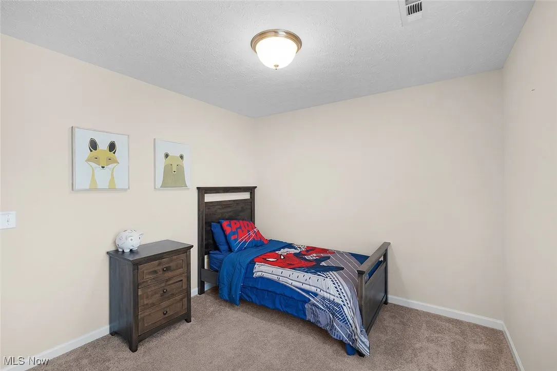Carpeted bedroom featuring baseboards and a textured ceiling