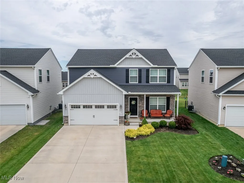 Craftsman inspired home featuring board and batten siding, a porch, driveway, stone siding, and a front lawn