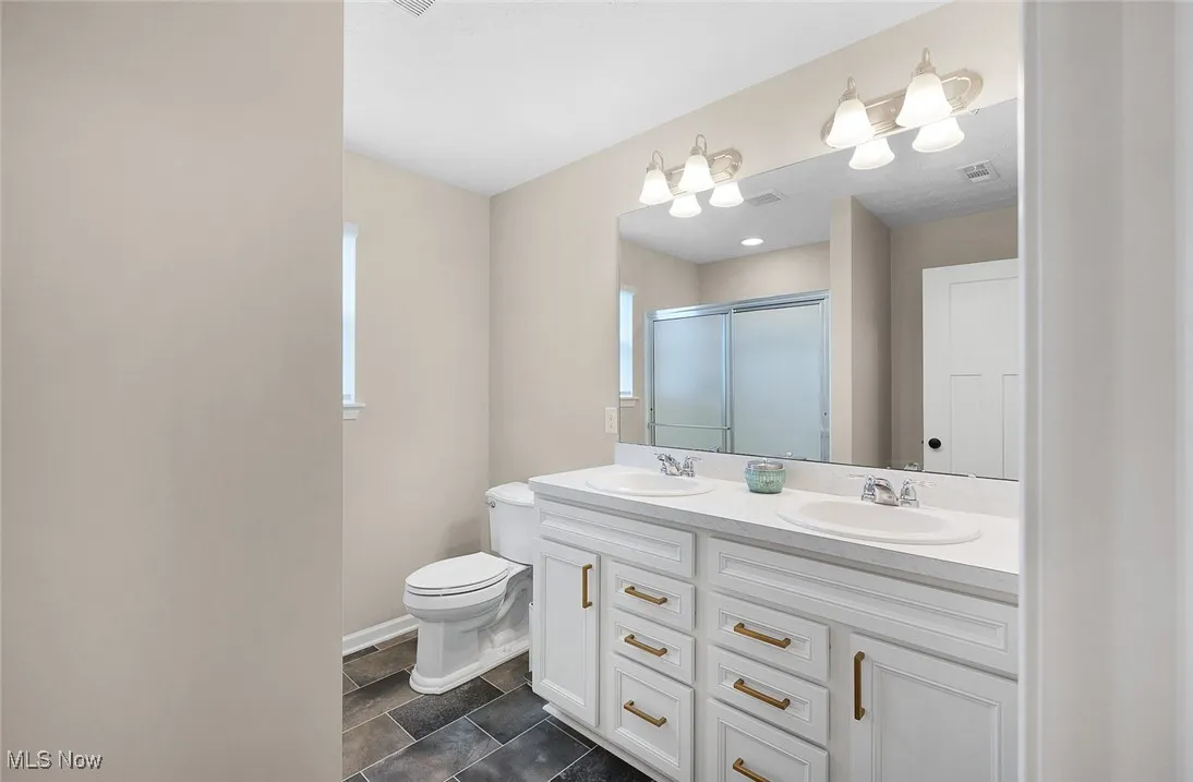 Bathroom featuring double vanity and a shower with door