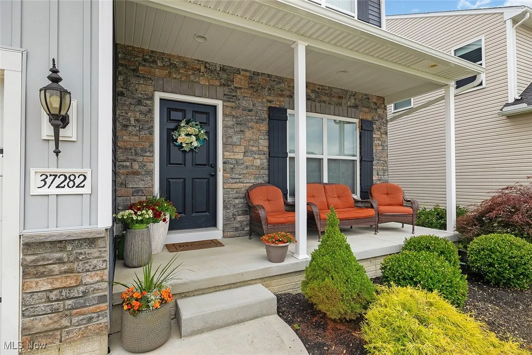 Doorway to property with covered porch and stone siding
