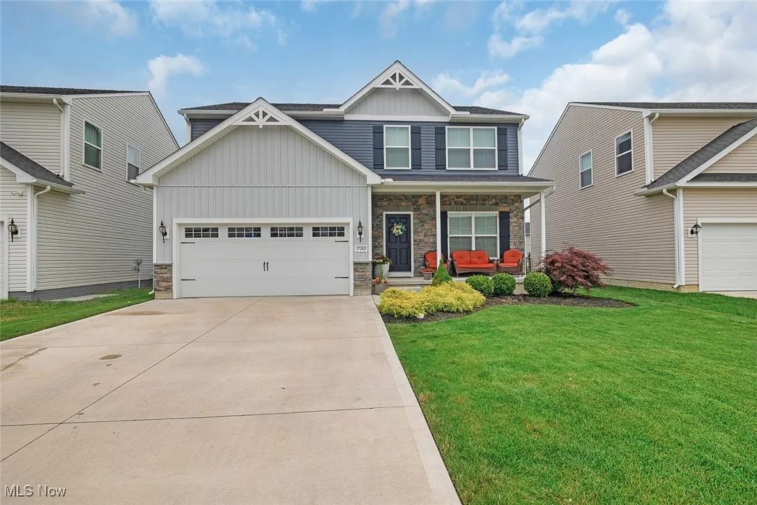 Craftsman house with board and batten siding, covered porch, driveway, and stone siding