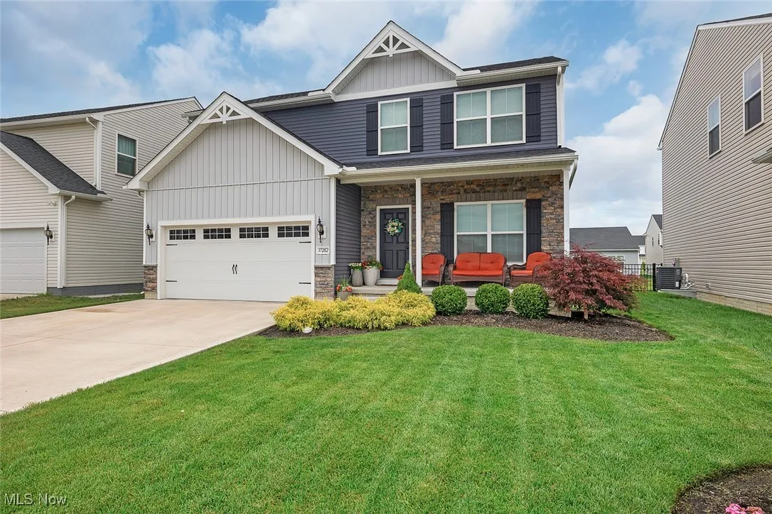 Craftsman inspired home with board and batten siding, covered porch, stone siding, concrete driveway, and a front yard