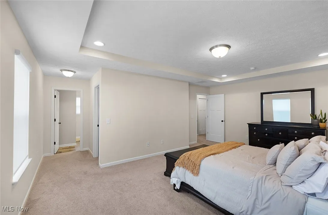 Bedroom featuring a raised ceiling, light carpet, recessed lighting, and a textured ceiling