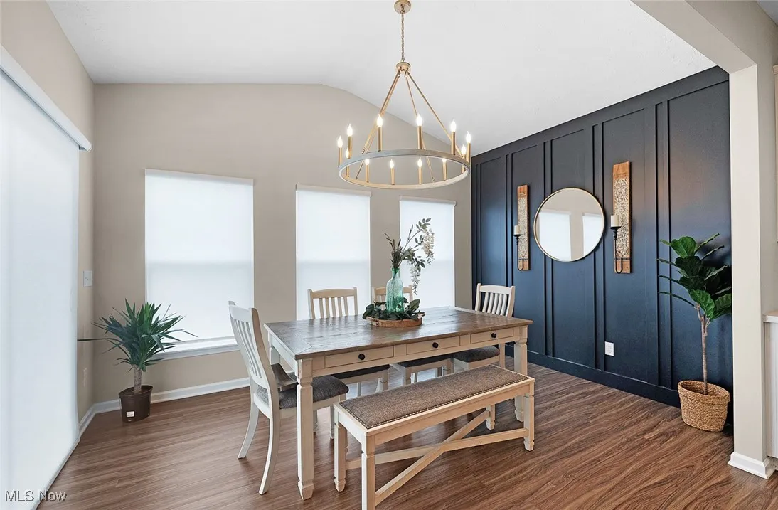 Dining space with a chandelier, dark wood finished floors, and vaulted ceiling