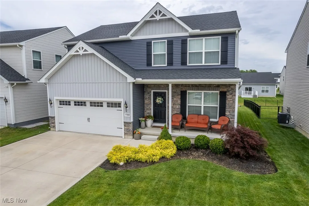 Craftsman house with a porch, stone siding, board and batten siding, and roof with shingles