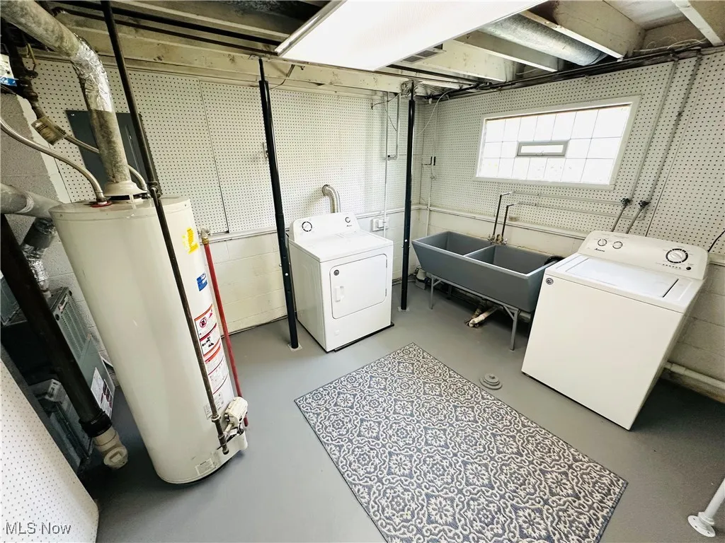 Laundry area featuring gas water heater, washing machine and clothes dryer, and concrete block wall