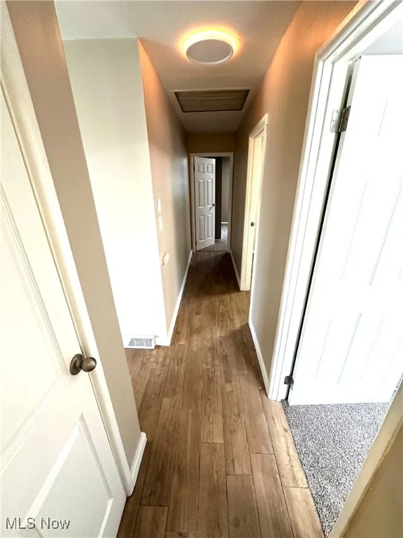 Corridor featuring dark wood-type flooring and baseboards