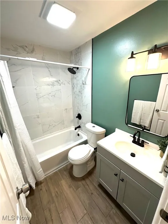 Full bathroom with shower / bath combo, vanity, and wood finished tile loors
