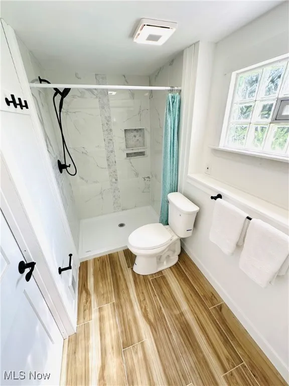 Full bath with wood tiled floors and a marble finish shower