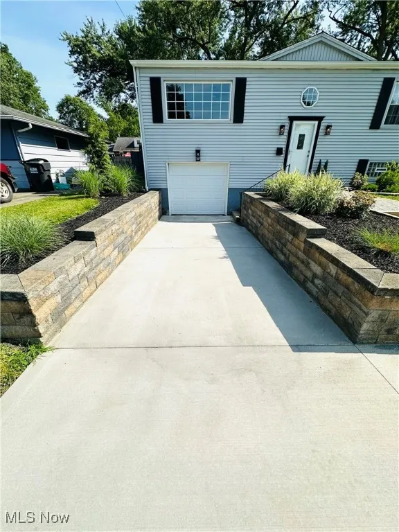 Split foyer home featuring new driveway, new retainer wall, and a garage