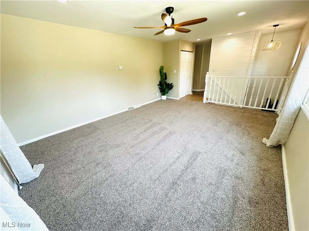 Carpeted living room featuring a new ceiling fan and recessed lighting