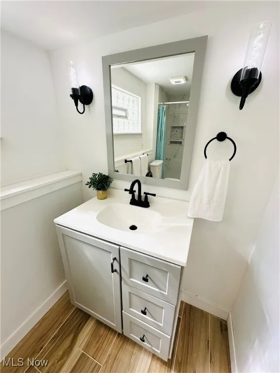 Full master bath featuring new vanity, wood finished tiled floors, and a shower with curtain