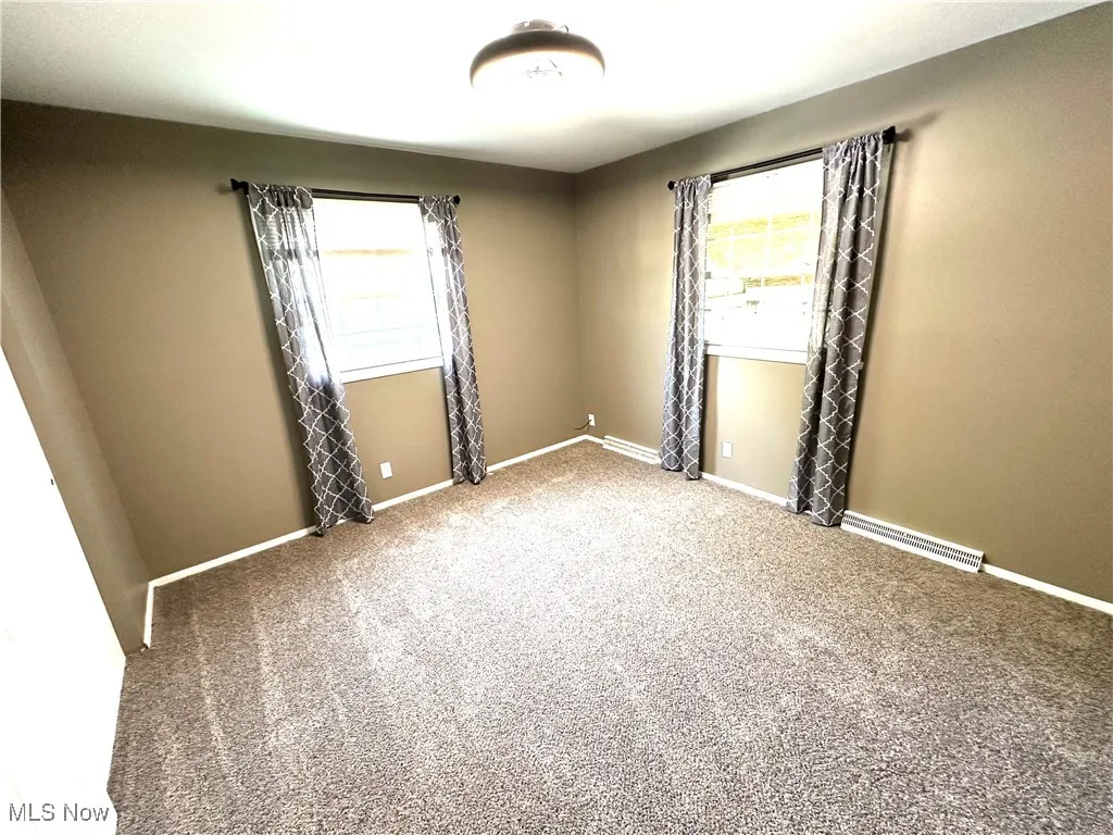 Carpeted empty bedroom with baseboards